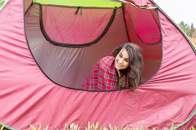 Adorable young lady sitting in the tent and smiling