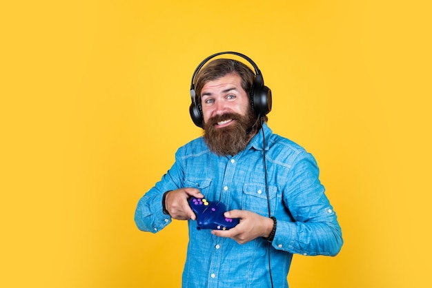 Adorn your Life with Game cheerful man wear modern earphones male in headphones with game console computer gaming concept playing online relax with favorite hobby bearded man gamer