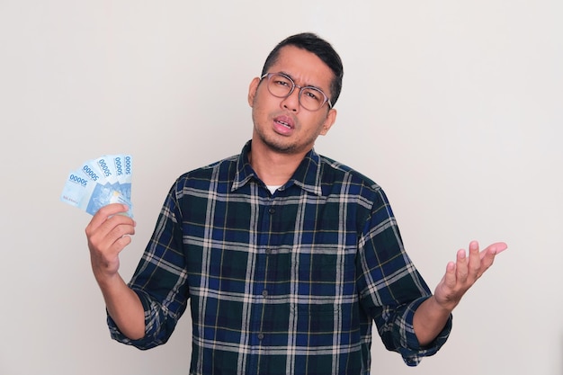 Adult Asian man holding money with disappointed gesture