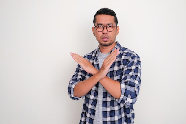 Adult Asian man looking camera with serious expression with his hand making block gesture