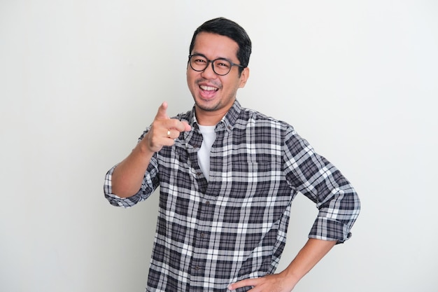 Adult Asian man showing excited expression while pointing finger forward