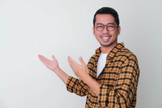 Adult Asian man showing something behind gesture with smiling face