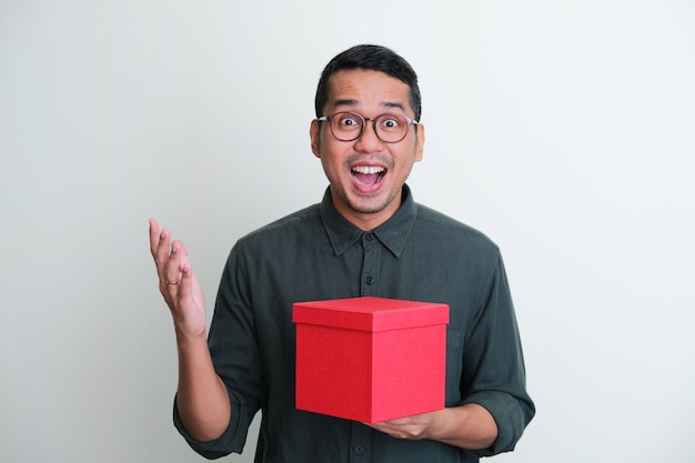 Adult Asian man showing wow face expression when holding a gift box