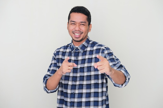 Adult Asian man smiling happy while pointing forward