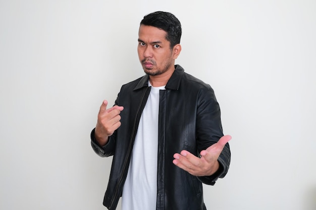 Adult Asian man wearing black leather jacket showing cruel expression while asking something forcefully