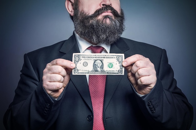 Adult bearded man in a suit holding a dollar Toned