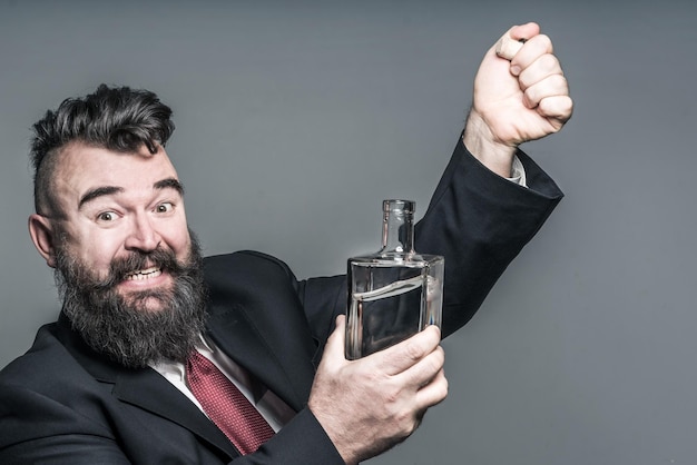 Adult bearded man in suit pulling a stopper from a bottle with alcohol