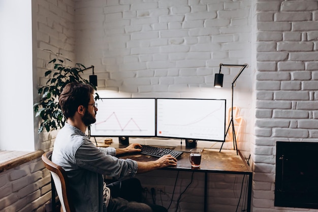 Adult bearded man working sitting at home desk at computer working online