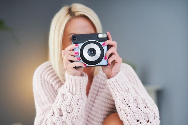 Adult beautiful woman taking instant photo at home