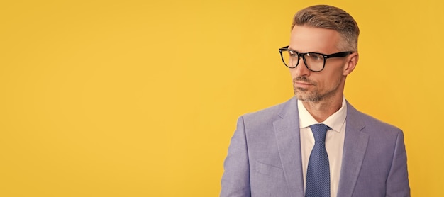 Adult businessman in elegant jacket and eyeglasses on yellow background business vision Man face