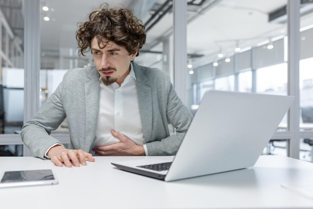 Adult businessman feeling unwell at his workplace in a modern office showcasing typical office work