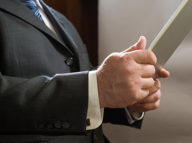 adult businessman standing in suit and use tablet