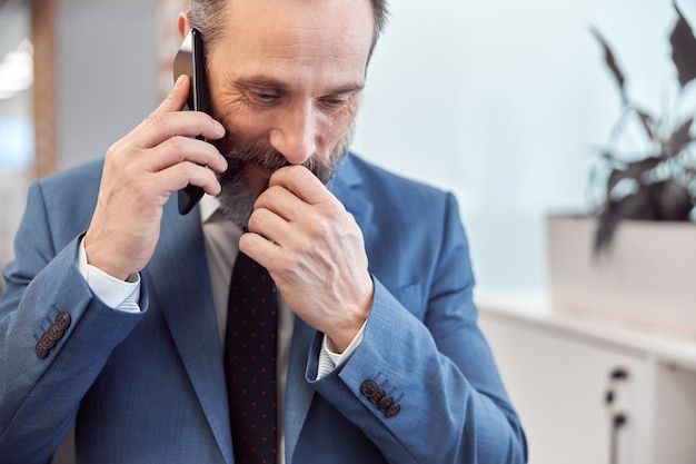 Adult businessman using smartphone in a modern office