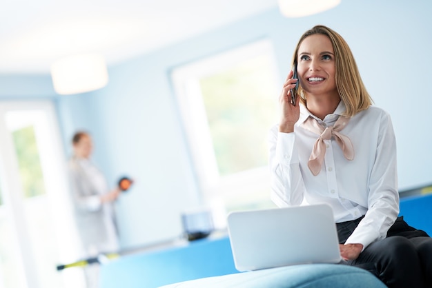 adult businesswoman using computer in playroom relax zone woman playing table tennis in the background