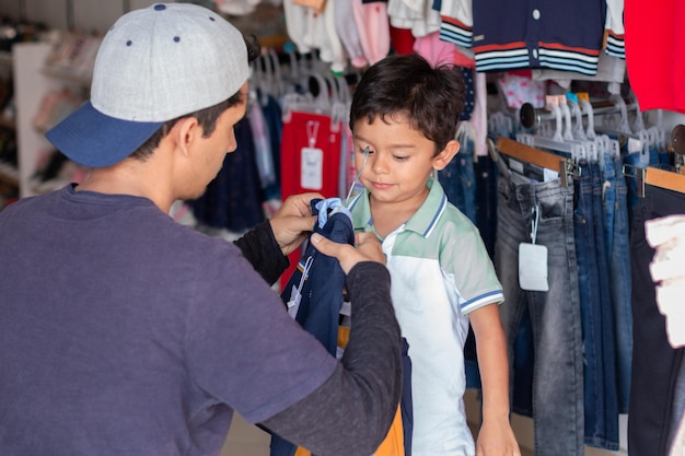 Adult buying clothes for his sonlatin man sizing a shirt or sweater for his son in a clothing store