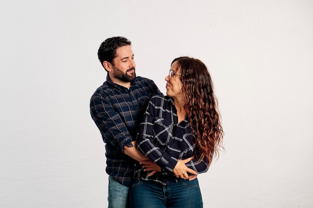 An adult caucasian couple in plaid shirts standing and showing thumbs up to the camera and smiling against a white background.