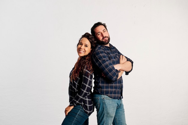 An adult caucasian couple in plaid shirts standing and showing thumbs up to the camera and smiling against a white background.