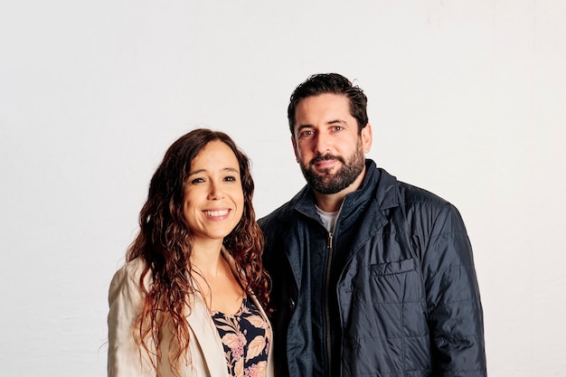 An adult caucasian couple in plaid shirts standing and showing thumbs up to the camera and smiling against a white background.