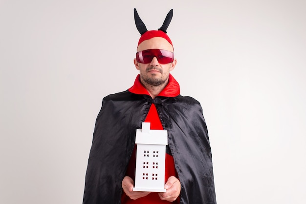 Adult caucasian man in halloween costume with decorative building in his hands isolated on white.