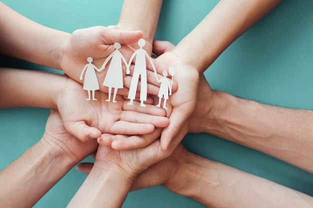 Adult and children hands holding paper family cutout