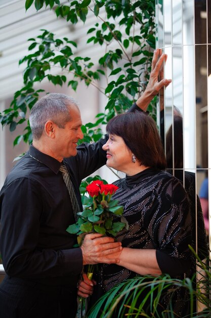 Photo adult couple a man gives his wife a bouquet roses