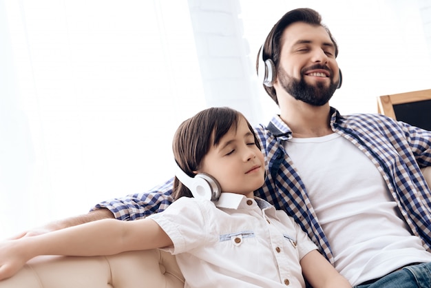 Adult father and teenager listening to music on headphones.