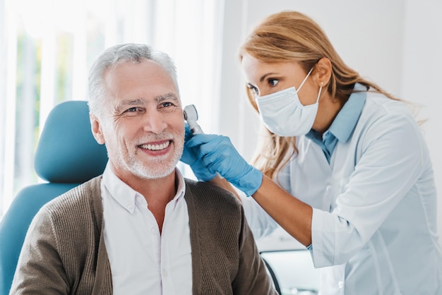 Adult female doctor examining patient's ear with otoscope