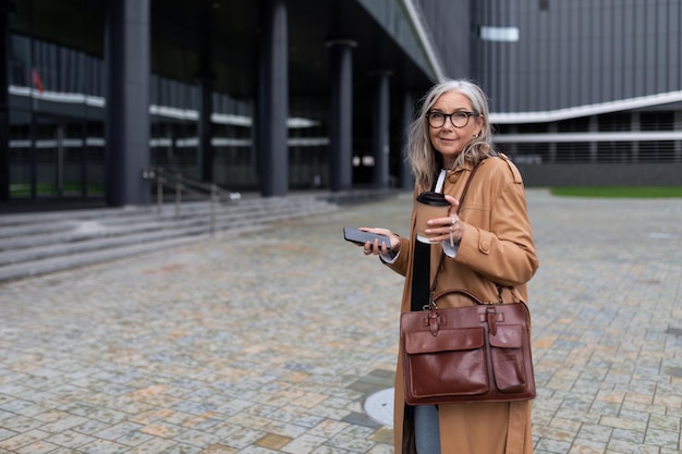 Adult grayhaired successful woman businesswoman on the background of an office building