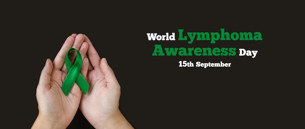 Adult hands holds green ribbon on black background World lymphoma awareness day September 15