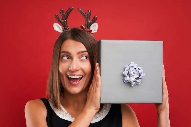 Adult happy woman with Christmas gift over red background