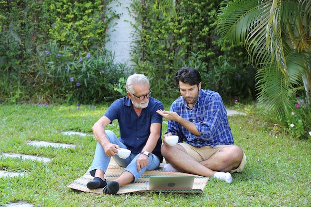 Adult hipster son and old senior father stay for work at home two generations have a beard talking together and relaxing with smile happy enjoy living to isolation quarantine at home father's day