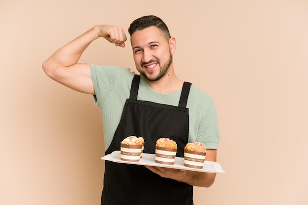 Adult latin cook man holding a muffins tray cut out isolated