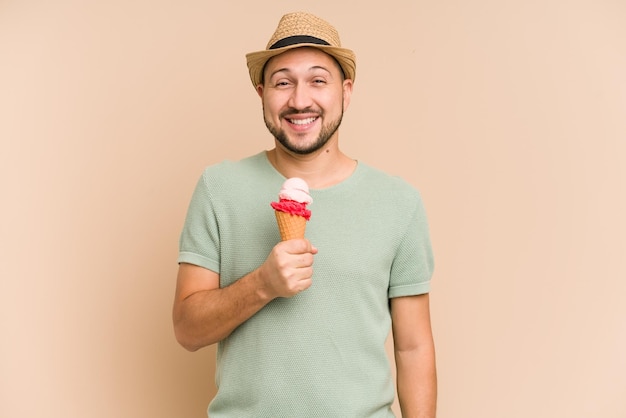 Adult latin man eating an ice cream isolated on beige background