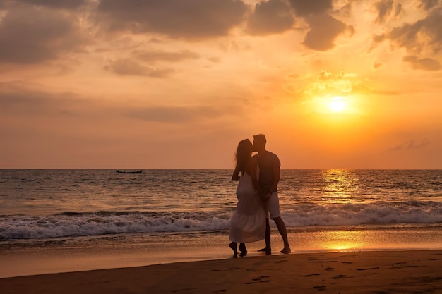 Adult lovely family couple holding hands kissing at ocean sunset background Man and woman in casual clothes walking together sandy beach outdoor