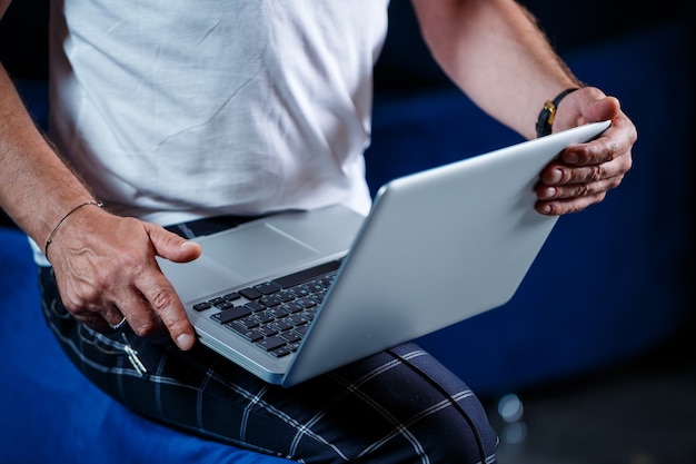 Adult male businessman, teacher, mentor working on a new project. Sits by a large window on the table. He looks at the laptop screen.