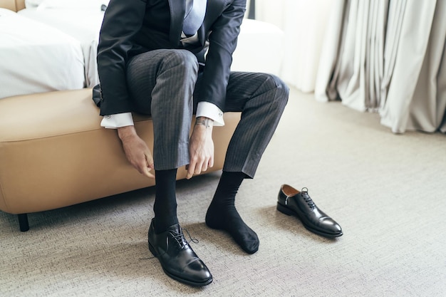 Adult male in an elegant suit sitting on a small chair and wearing socks