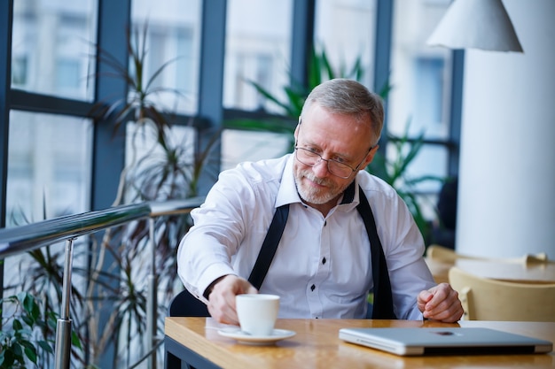 Adult male manager businessman worked successfully and at the end of the day drinks coffee without a jacket