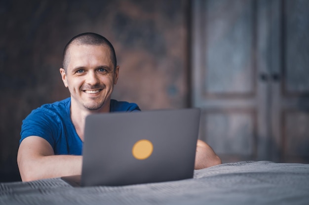 Adult man in blue tshirt working on laptop