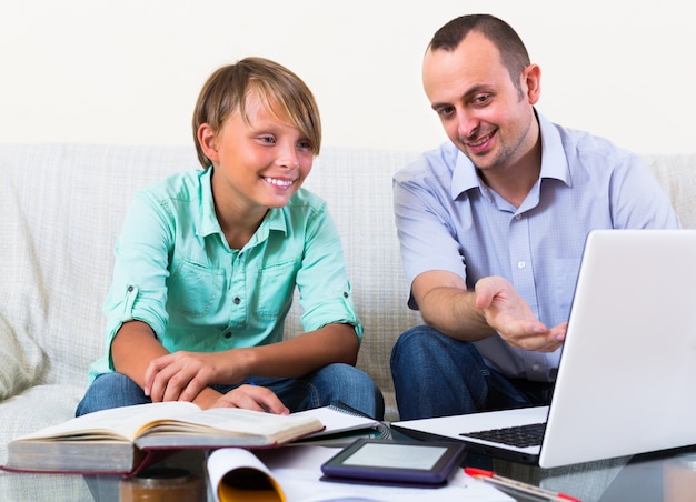 Adult man and boy with laptop indoors&#xA;