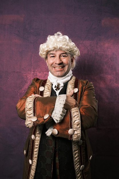 Adult man in classical medieval clothing posing with his arms crossed on an isolated background.