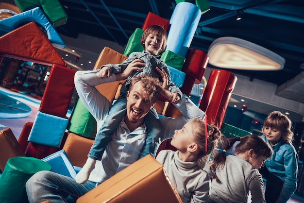 Photo adult man and cute children on indoor playground