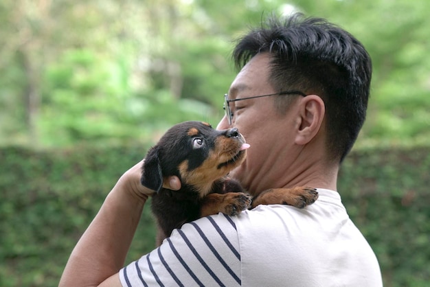 Adult man holding little puppy dog on his shoulder