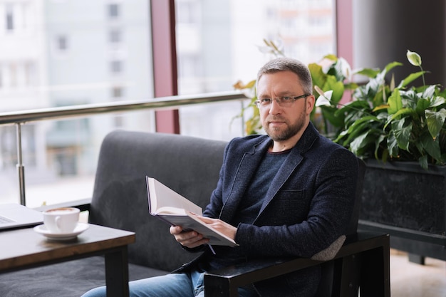 Adult man reading a book over a cup of coffee in the morning