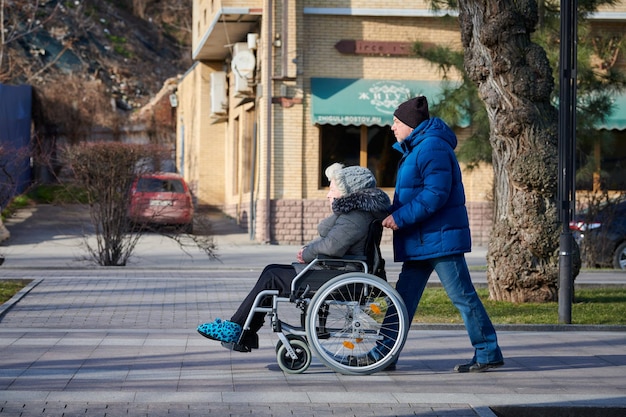 Adult man rolls his disabled mother on wheelchair careful relationships with disabled person