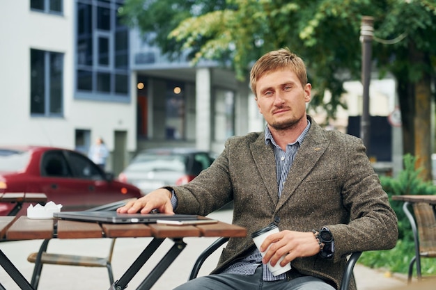 Adult man sitting outdoors at the cafe table at daytime