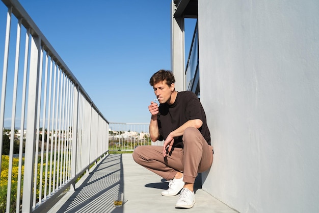 Adult man smoking and drinking alcohol near apartment complex