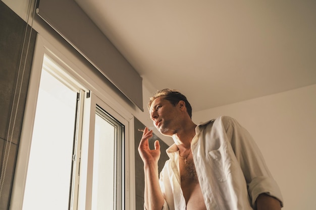 Adult man smoking RYO cigarette or cannabis joint at home