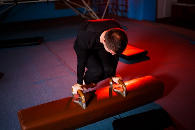 Photo adult man in sportswear doing exercises on gymnastic apparatus in the acrobatic gym