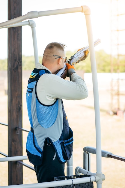 Adult man in sunglasses and a rifle vest practicing fire weapon shooting