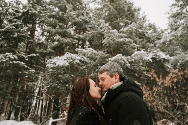 Adult man and woman on the background of a winter snow-covered pine forest